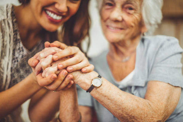 Close-up of a smiling nurse holding a senior woman's hand