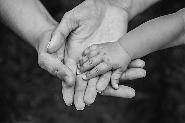 Three hands of the same family - father, mother and baby stay together. Close-up. The concept of family unity, protection, support, prosperity, love and parental happiness.